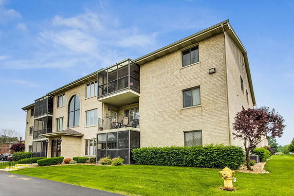 Front view of a multi-story apartment building with balconies and large windows.