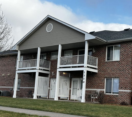 Front view of a two-story brick apartment building with balconies.