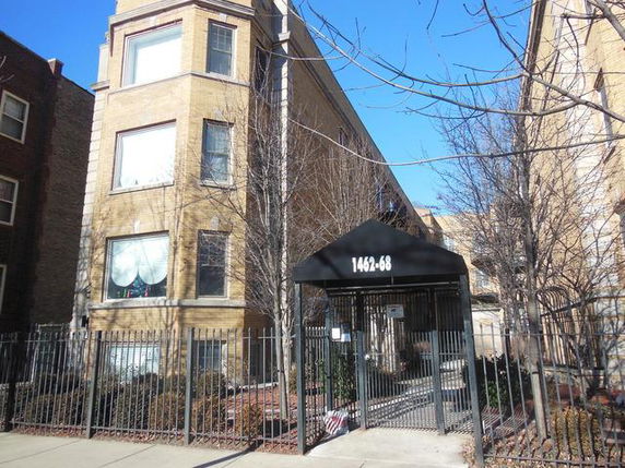 Front view of a multi-story residential building with a gated entrance.