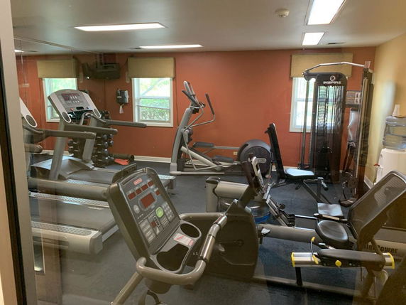 Indoor gym area with exercise equipment including treadmills and cycling machines.