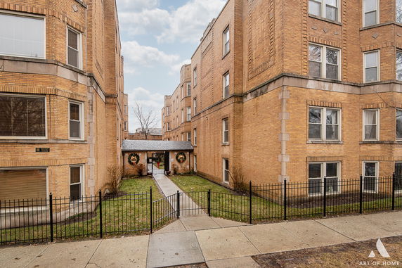 Front view of multi-story brick buildings with a central gated entrance.