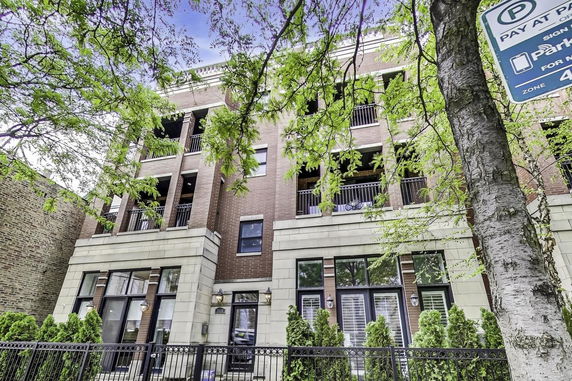 Front view of a multi-story residential building with balconies and brick exterior.