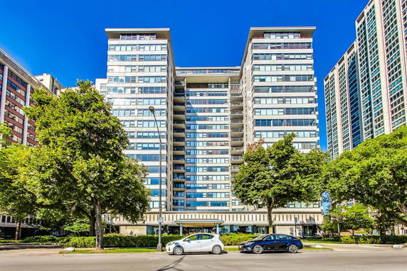Front view of a multi-story apartment building with numerous balconies and large windows.