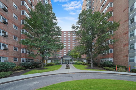 Front view of a large brick apartment building complex with multiple stories and central entrance.