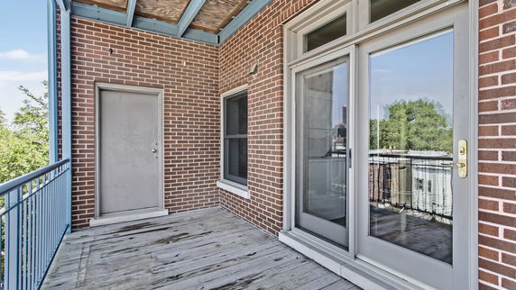 Outdoor rooftop area with wooden flooring and brick walls.