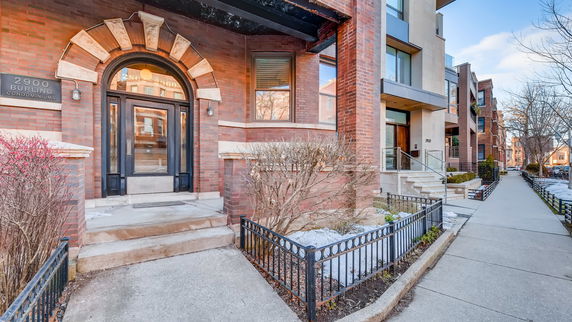 Front view of a brick condominium building with an arched entrance.
