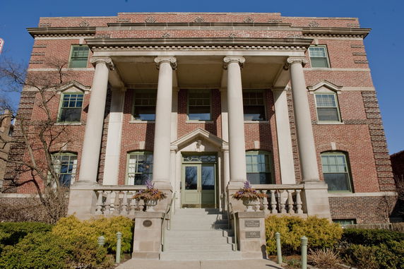 Front view of a brick building with four large columns and multiple windows.