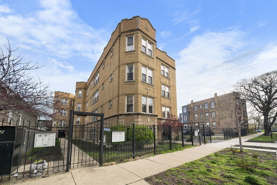 Front view of a multi-story apartment building with a gated entrance.