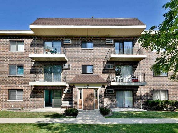 Front view of a multi-story brick apartment building with balconies.