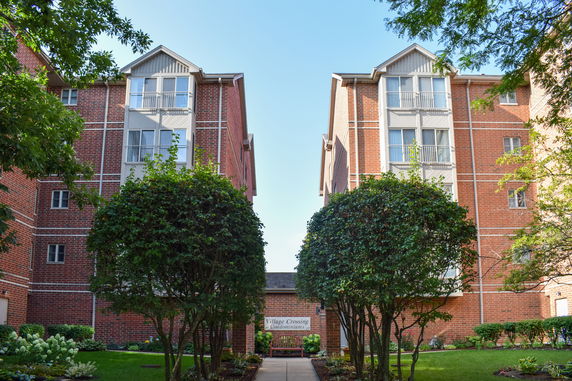 Front view of a multi-story brick apartment building with balconies.