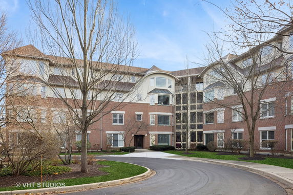 Front view of a multi-story brick building with large windows and sloped roofs.