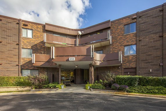 Front view of a multi-story brick apartment building with balconies.