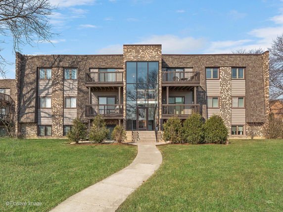 Front view of a two-story building with a central glass entrance and balconies.