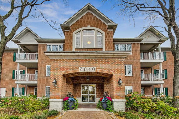 Front view of a multi-story brick building with balconies and a central entrance.