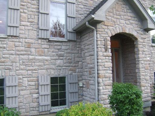 Front view of a stone house with shuttered windows and a gable entrance.