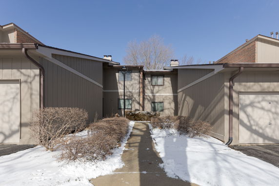 Front view of a two-story house with brown siding and two visible garage doors.