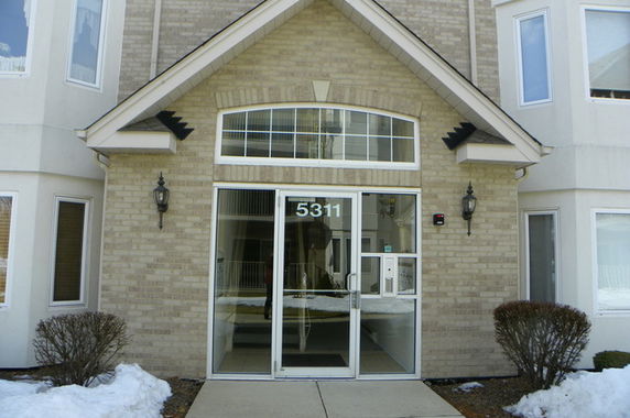 Front entrance of a building with glass doors and brick exterior.