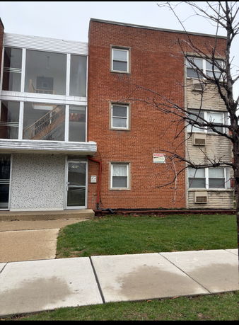Front view of a three-story brick apartment building with large windows.