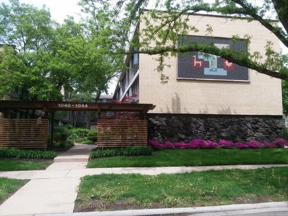Front view of a two-story building with brick exterior and a decorative art piece on the wall.