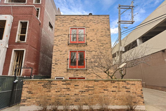 Front view of a three-story brick building with red window frames.