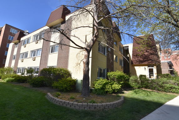 Front view of a multi-story apartment building with a brown and yellow facade.