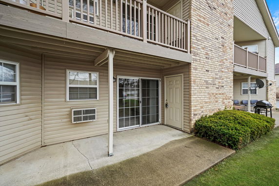 Rear view of a multi-story apartment building with a patio and balcony.