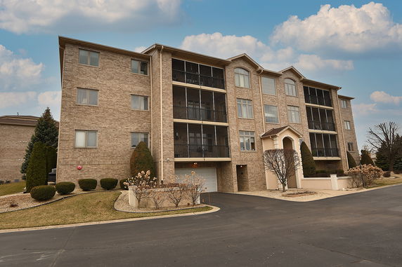 Front view of a multi-story brick apartment building with balconies.