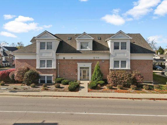 Front view of a two-story brick building with white trim and multiple dormer windows.