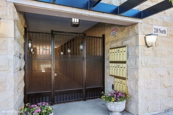 Front entrance of a building with a gated entry and mailboxes.