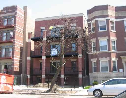 Front view of a multi-story brick residential building with balconies.