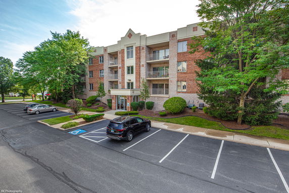 Front view of a multi-story brick apartment building with balconies.