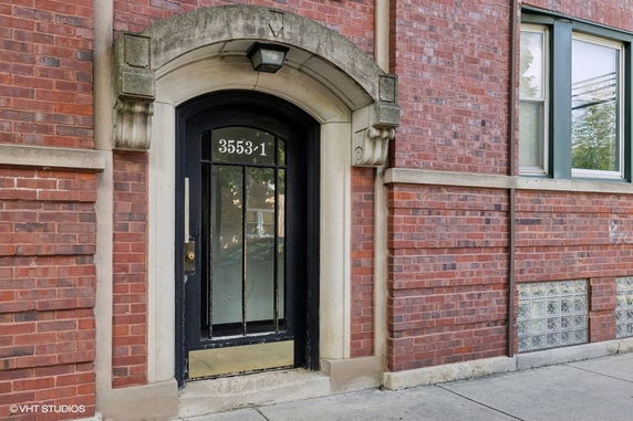 Front view of a building entrance with a red brick facade and an arched doorway.