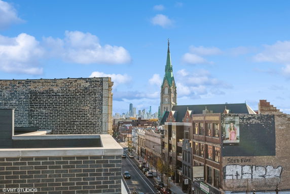 Panoramic cityscape view with a church spire and urban buildings.
