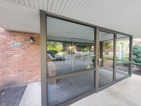 Front view of a building entrance with glass doors and a brick wall.