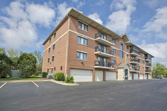 Front view of a multi-story brick apartment building with balconies and garages.