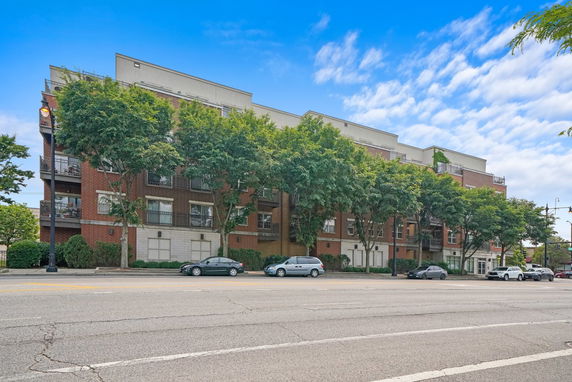 Front view of a multi-story building with a brick facade and large windows.