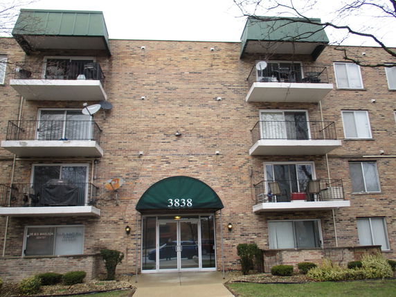 Front view of a multi-story brick apartment building with balconies.