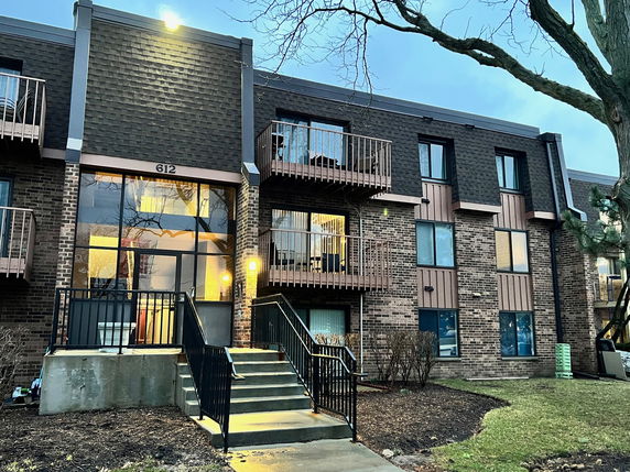 Front view of a multi-level brick apartment building with multiple balconies.