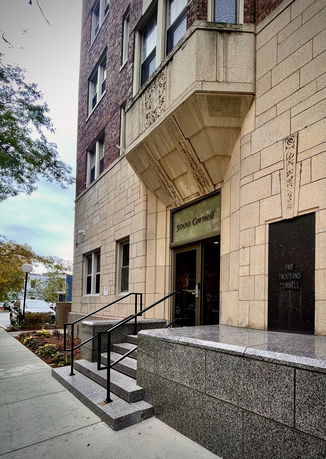 Front view of a multi-story building with an entrance featuring decorative stonework.
