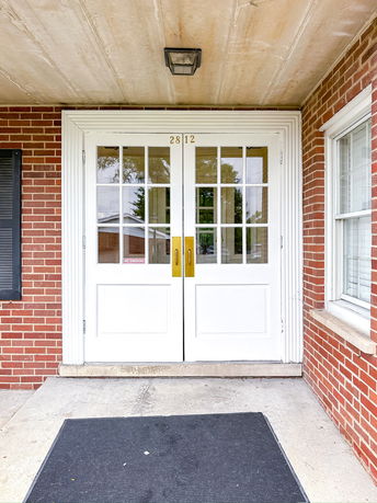 Front view of a building entrance with a double door and brick exterior.