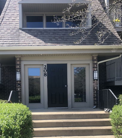 Front view of a residential building with brick exterior and a single front door marked with the number 208.
