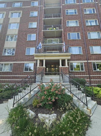 Front view of a multi-story brick building with balconies and a central entrance.