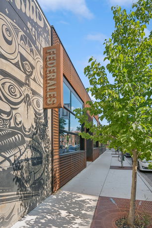 Front view of a building with artistic mural and large windows.