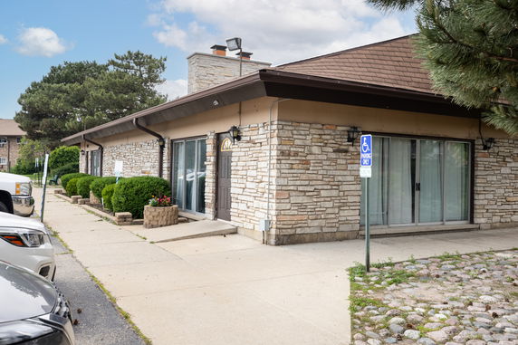 Front view of a single-story building with stone exterior and sliding glass doors.