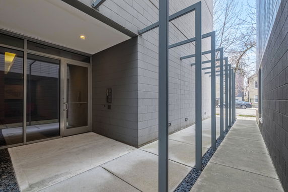 Entrance to a modern building with a glass door and metal frame canopy.