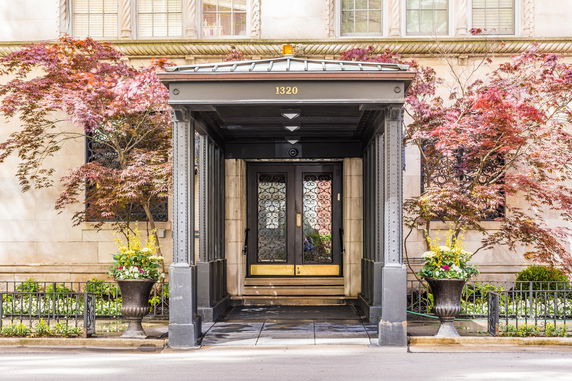 Front view of a building entrance with decorative metal doors and canopy.