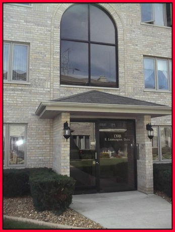 Front view of a multi-story building with large glass entrance and brick facade.