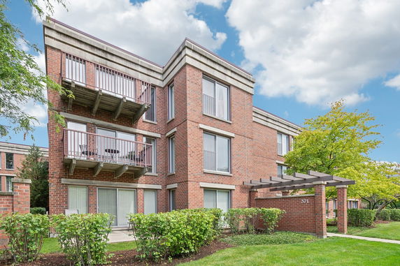 Front view of a multi-story brick apartment building with balconies.