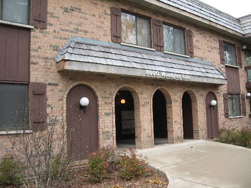 Front view of a two-story brick building with arched doorways and wall-mounted lights.