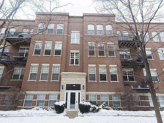 Front view of a multi-story brick apartment building with balconies.